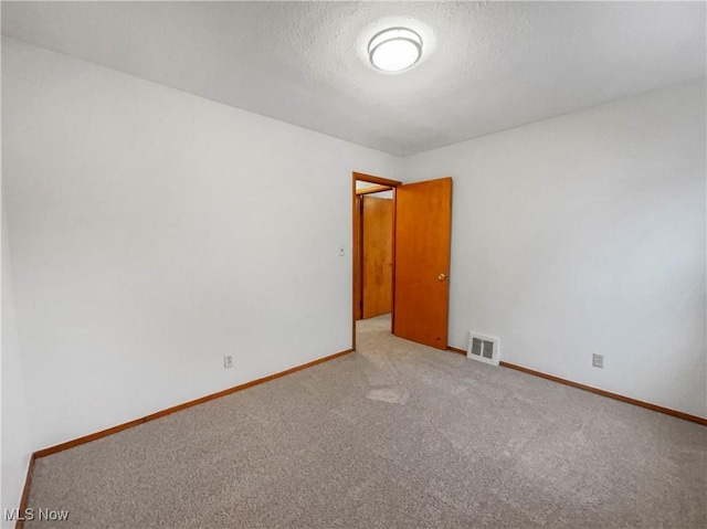 empty room featuring visible vents, baseboards, a textured ceiling, and carpet flooring