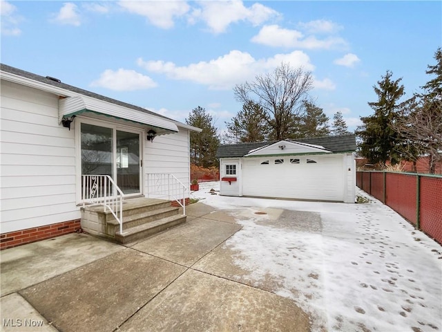 view of side of property featuring a detached garage, an outdoor structure, and fence