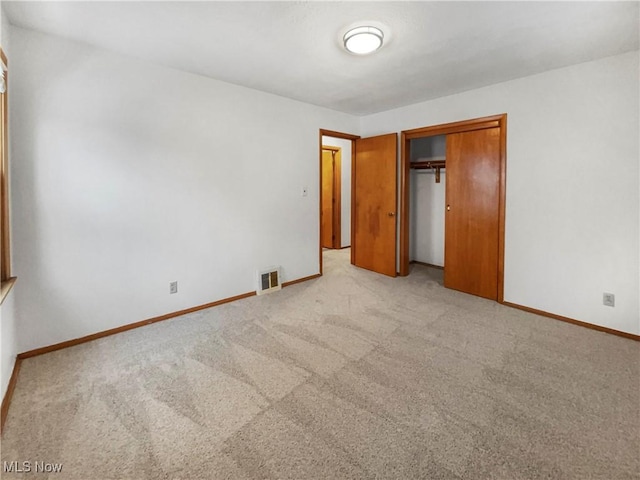 unfurnished bedroom featuring a closet, visible vents, light carpet, and baseboards