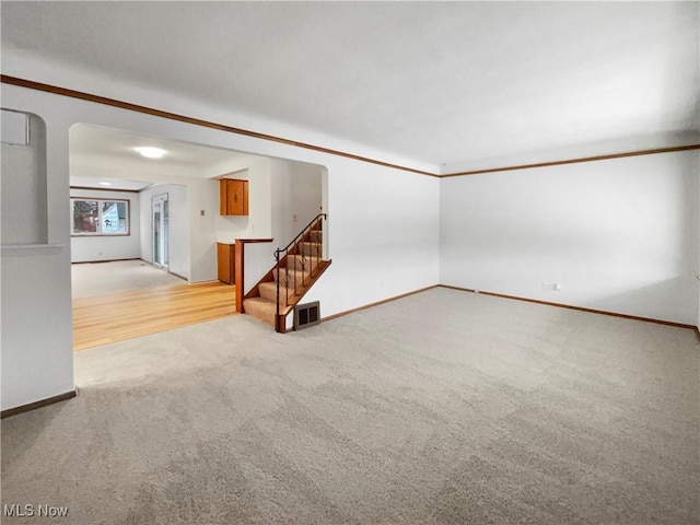 spare room featuring visible vents, light carpet, baseboards, and stairs