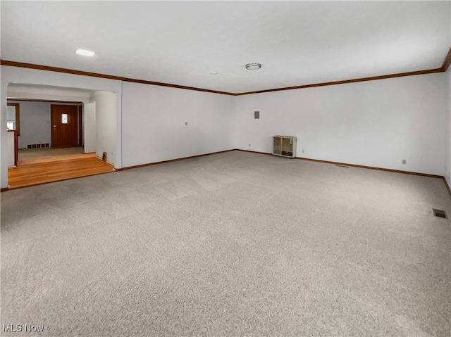 unfurnished room with visible vents, light colored carpet, crown molding, and baseboards