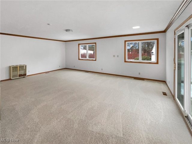 empty room featuring heating unit, plenty of natural light, crown molding, and visible vents