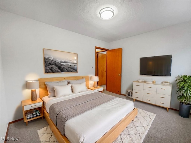 bedroom featuring light colored carpet, baseboards, and a textured ceiling