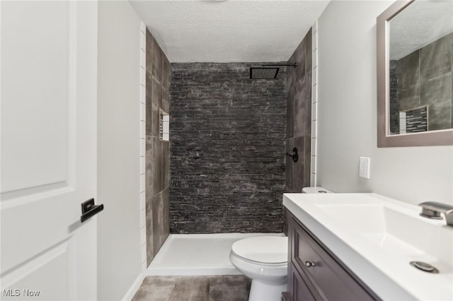 bathroom featuring a stall shower, toilet, vanity, and a textured ceiling