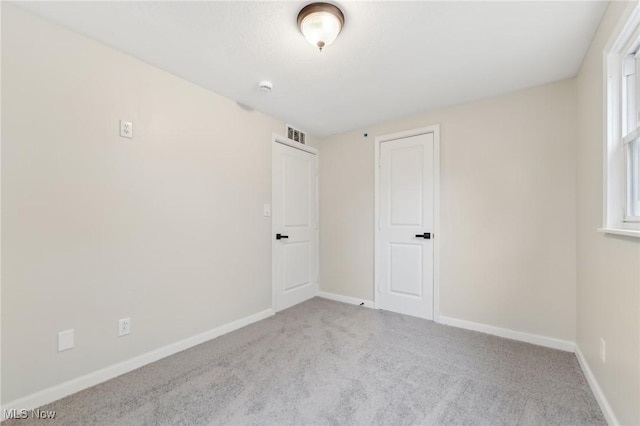 spare room with visible vents, carpet, and baseboards