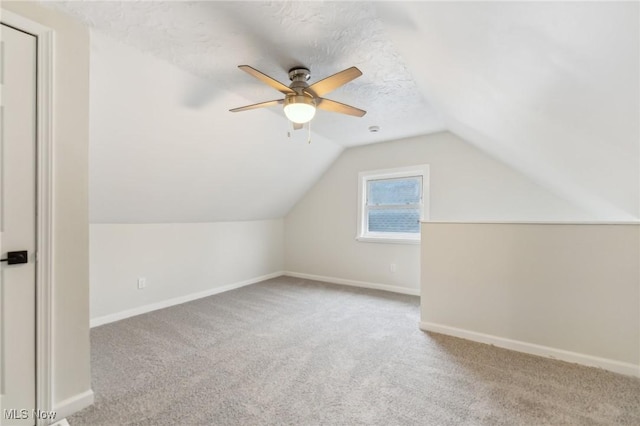 additional living space with baseboards, carpet floors, lofted ceiling, ceiling fan, and a textured ceiling