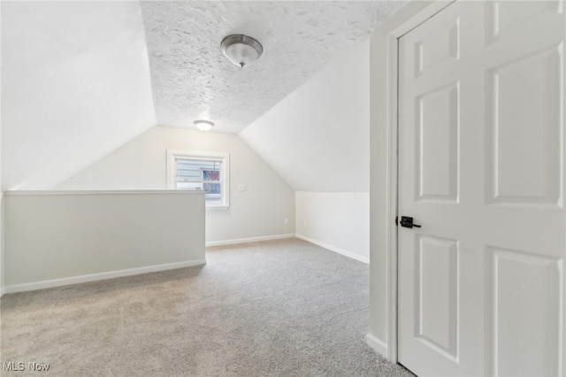 additional living space with vaulted ceiling, carpet, baseboards, and a textured ceiling