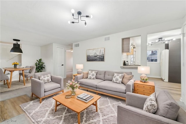 living room with visible vents, baseboards, and light wood-style floors