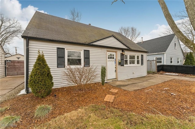 view of front of home with a patio area, roof with shingles, and fence