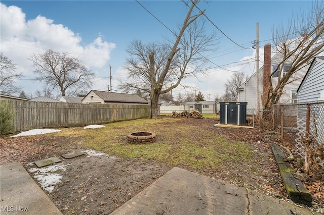 view of yard featuring an outdoor structure, a fenced backyard, and an outdoor fire pit