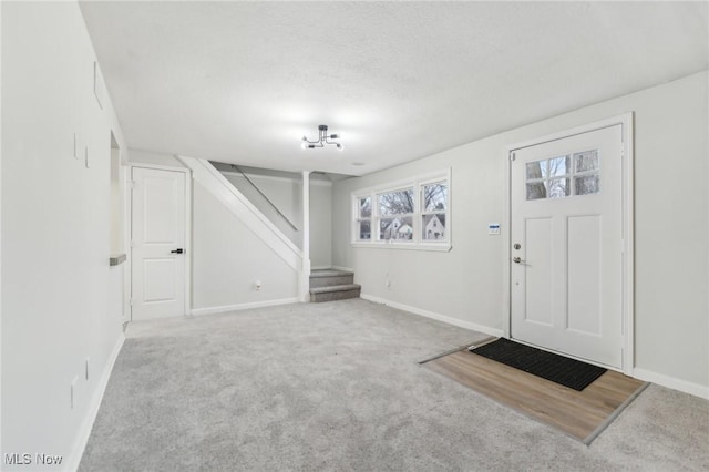 entryway with stairs, baseboards, carpet floors, and a textured ceiling