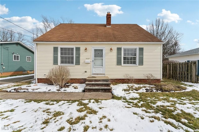 bungalow-style house featuring entry steps, a chimney, and fence