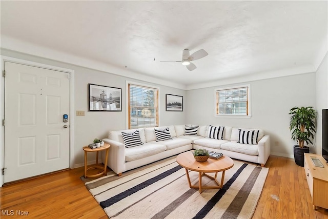 living room featuring baseboards, light wood-style flooring, and a ceiling fan