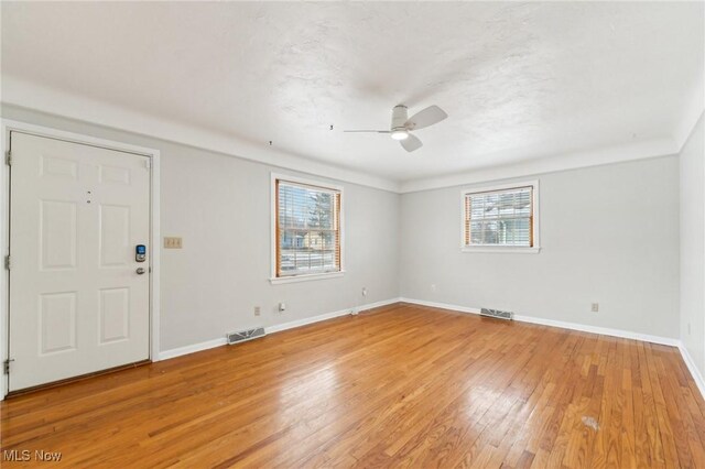 interior space with ceiling fan, light wood-style floors, visible vents, and baseboards