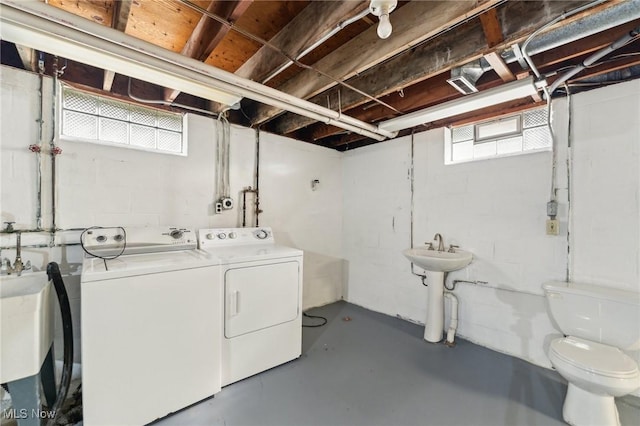 laundry area with a sink, laundry area, washing machine and dryer, and a healthy amount of sunlight