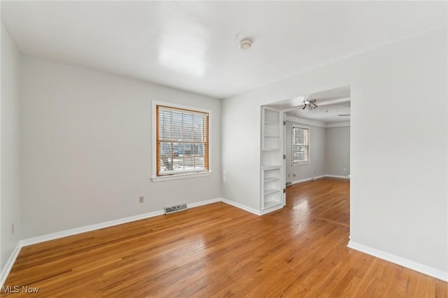 spare room featuring visible vents, a healthy amount of sunlight, light wood-type flooring, and baseboards