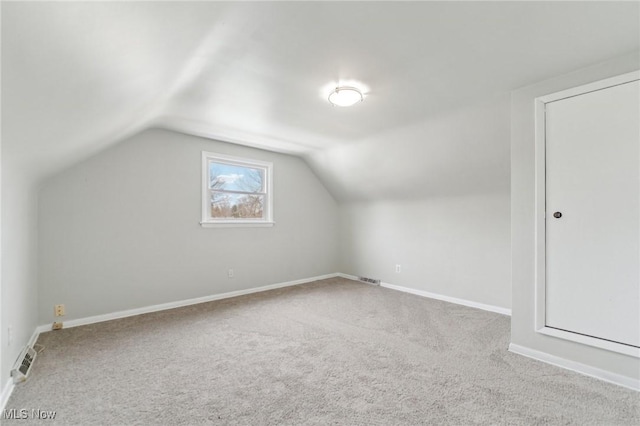 additional living space with visible vents, carpet flooring, baseboards, and vaulted ceiling