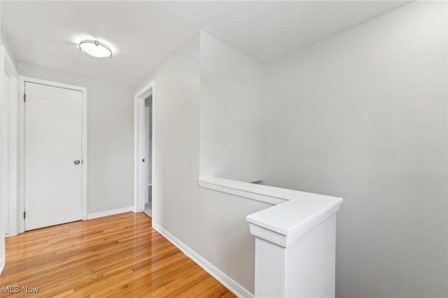 corridor with baseboards and light wood finished floors