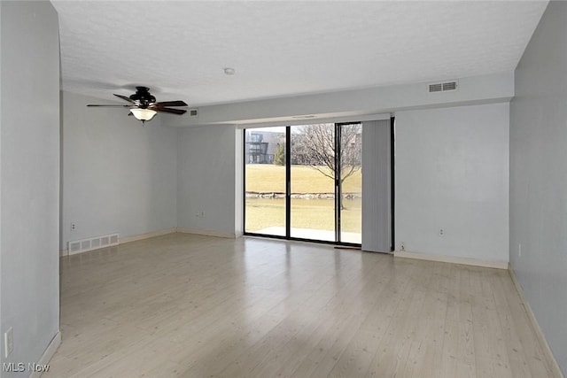 spare room with baseboards, visible vents, and light wood finished floors