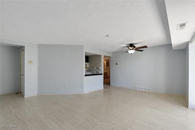 empty room with visible vents, a textured ceiling, a ceiling fan, and wood finished floors