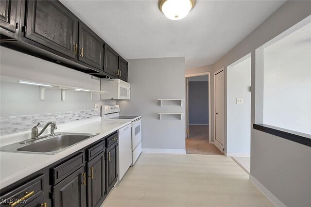 kitchen with a sink, baseboards, white appliances, and light countertops