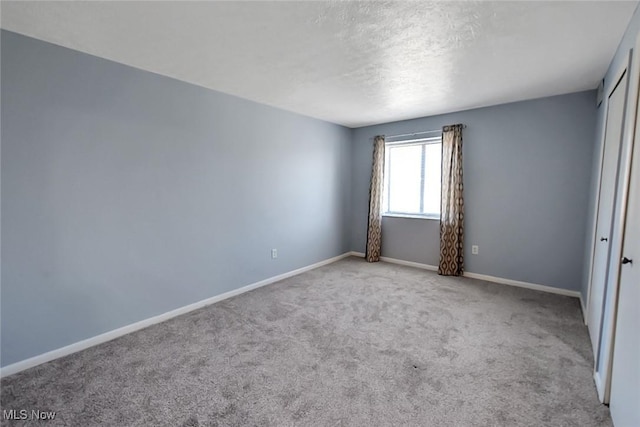 unfurnished room featuring a textured ceiling, baseboards, and carpet