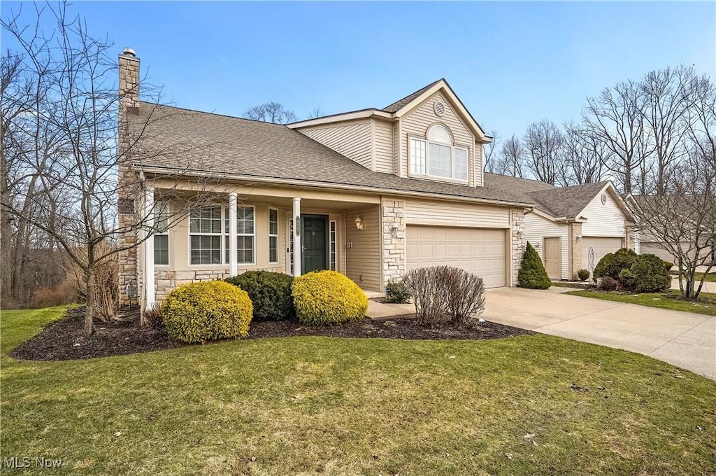 traditional-style house featuring roof with shingles, an attached garage, concrete driveway, a front lawn, and stone siding