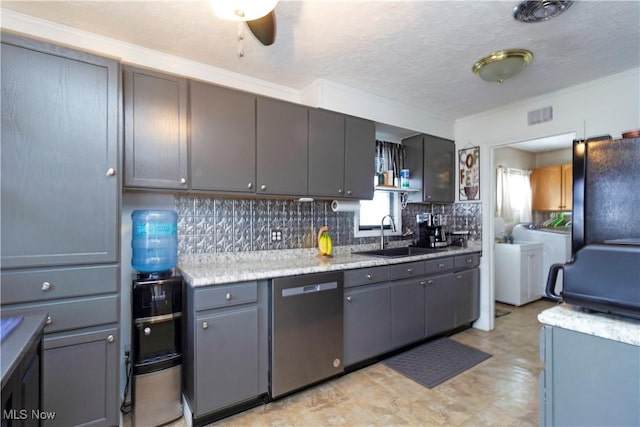 kitchen featuring backsplash, gray cabinetry, washing machine and dryer, dishwasher, and a sink