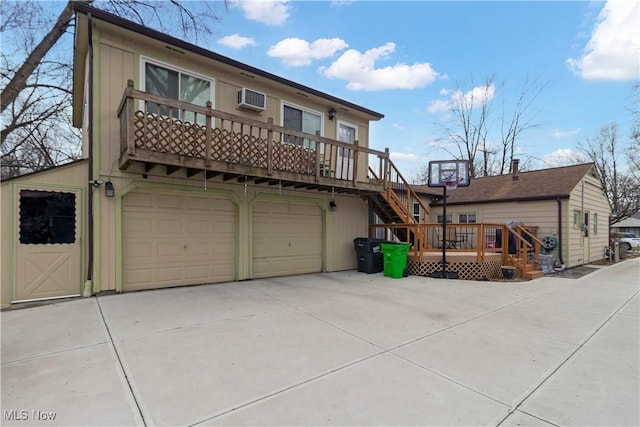 view of front of home with a wall unit AC, an attached garage, stairs, concrete driveway, and a deck