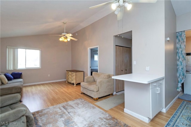 living area featuring vaulted ceiling, light wood-style flooring, baseboards, and ceiling fan