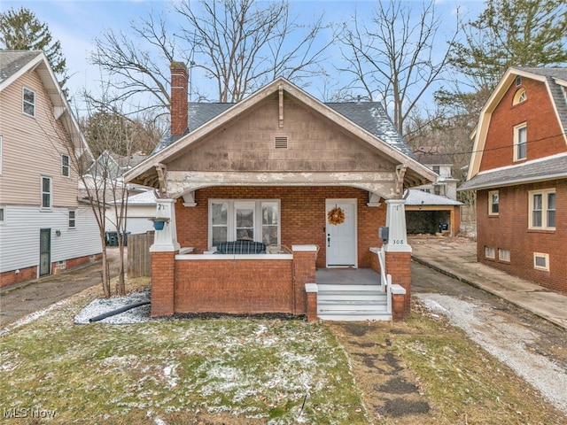 bungalow with brick siding, covered porch, and a chimney