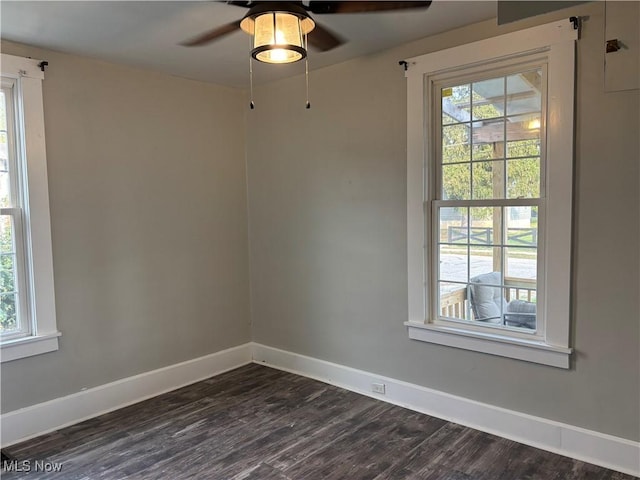 spare room with baseboards, dark wood finished floors, and a ceiling fan