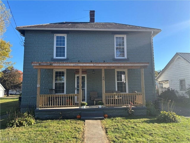 view of front of property featuring a front lawn, covered porch, and a chimney