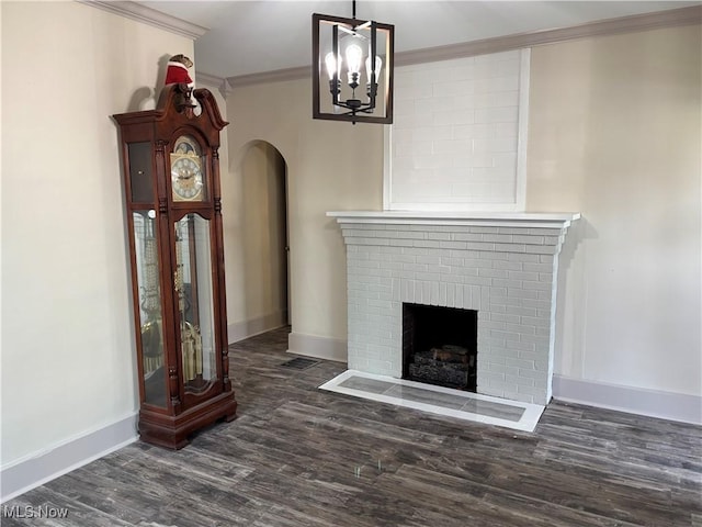 unfurnished living room with wood finished floors, baseboards, arched walkways, ornamental molding, and a brick fireplace