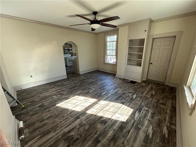 unfurnished bedroom with baseboards, dark wood finished floors, arched walkways, ceiling fan, and ornamental molding