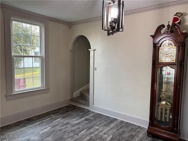 unfurnished dining area with baseboards, stairs, ornamental molding, arched walkways, and dark wood-style flooring