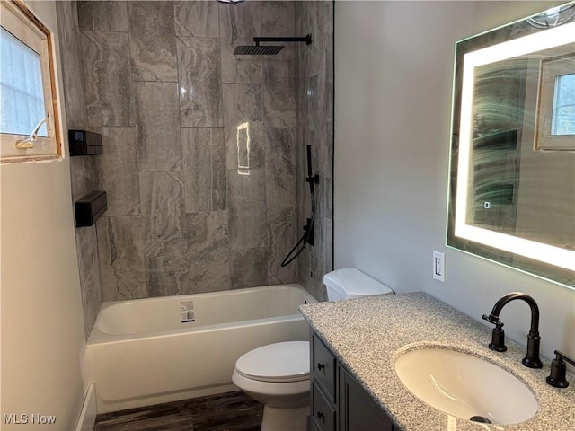 bathroom with a wealth of natural light, toilet, wood finished floors, tub / shower combination, and vanity