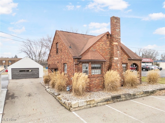 537 Main St, Navarre, OH 44662 - view of home's exterior featuring a detached garage, an outdoor structure, a shingled roof, brick siding, and a chimney