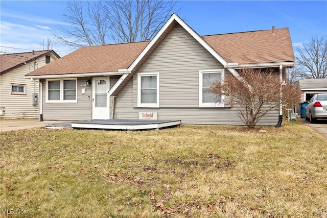 view of front facade with roof with shingles and a front yard