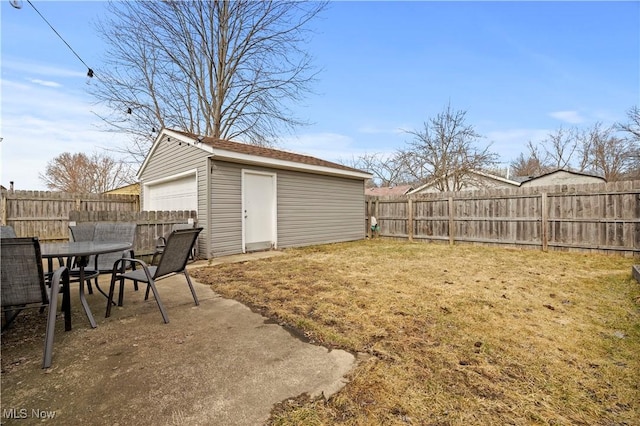 view of yard with a fenced backyard, outdoor dining area, a garage, and an outdoor structure