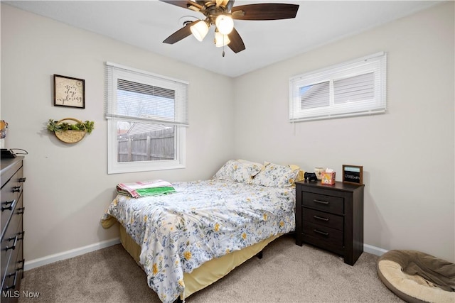 bedroom featuring light carpet, a ceiling fan, and baseboards