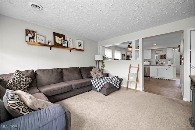 living area featuring baseboards, visible vents, ceiling fan, a textured ceiling, and carpet flooring