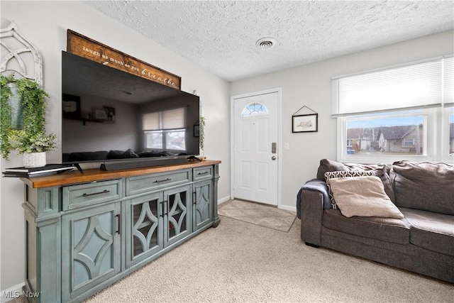 living area with baseboards, light colored carpet, visible vents, and a textured ceiling