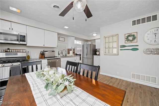 dining space featuring wood finished floors, visible vents, and a textured ceiling