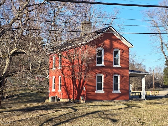 view of property exterior featuring central AC unit, a lawn, and a chimney