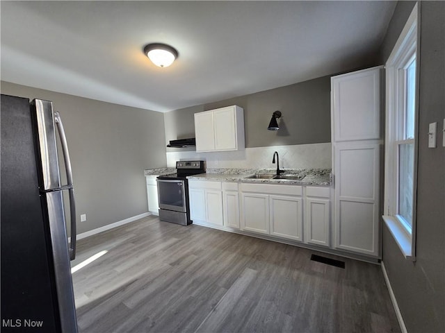 kitchen with a sink, wood finished floors, white cabinetry, ventilation hood, and appliances with stainless steel finishes