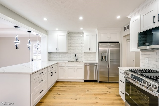 kitchen with a peninsula, light wood-style flooring, a sink, appliances with stainless steel finishes, and white cabinetry