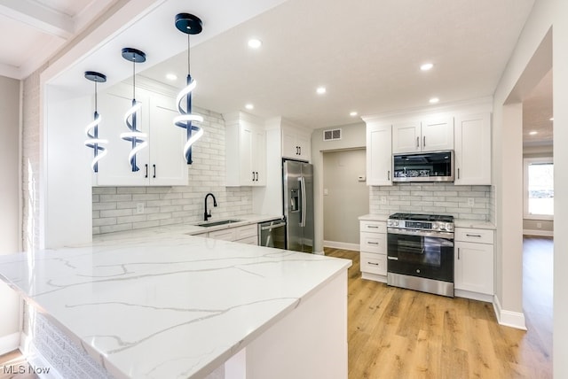 kitchen featuring visible vents, a peninsula, a sink, stainless steel appliances, and light wood-type flooring