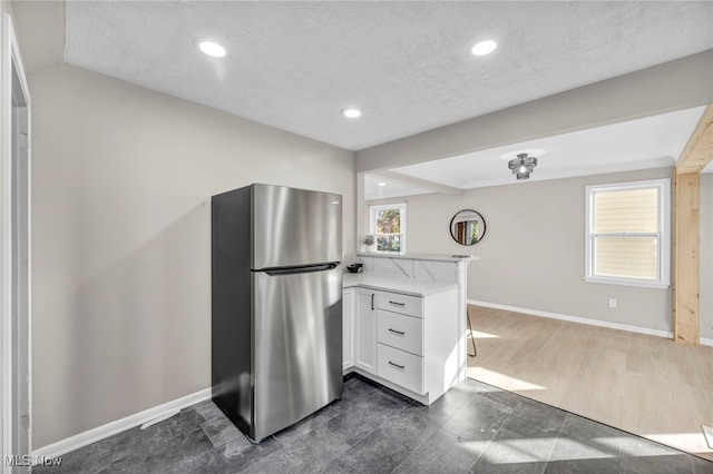 kitchen featuring a wealth of natural light, white cabinets, light countertops, and freestanding refrigerator