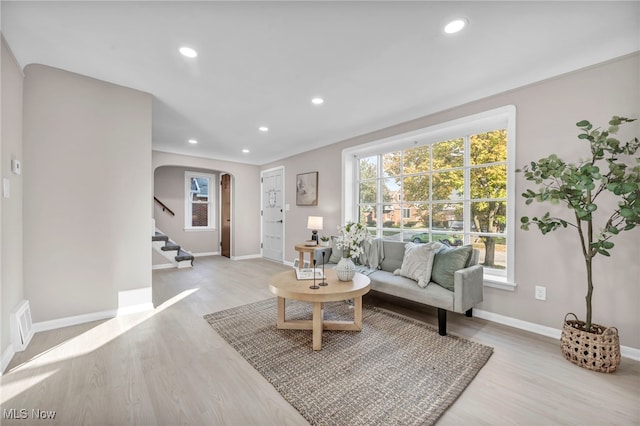 living room featuring recessed lighting, light wood-type flooring, arched walkways, and stairs